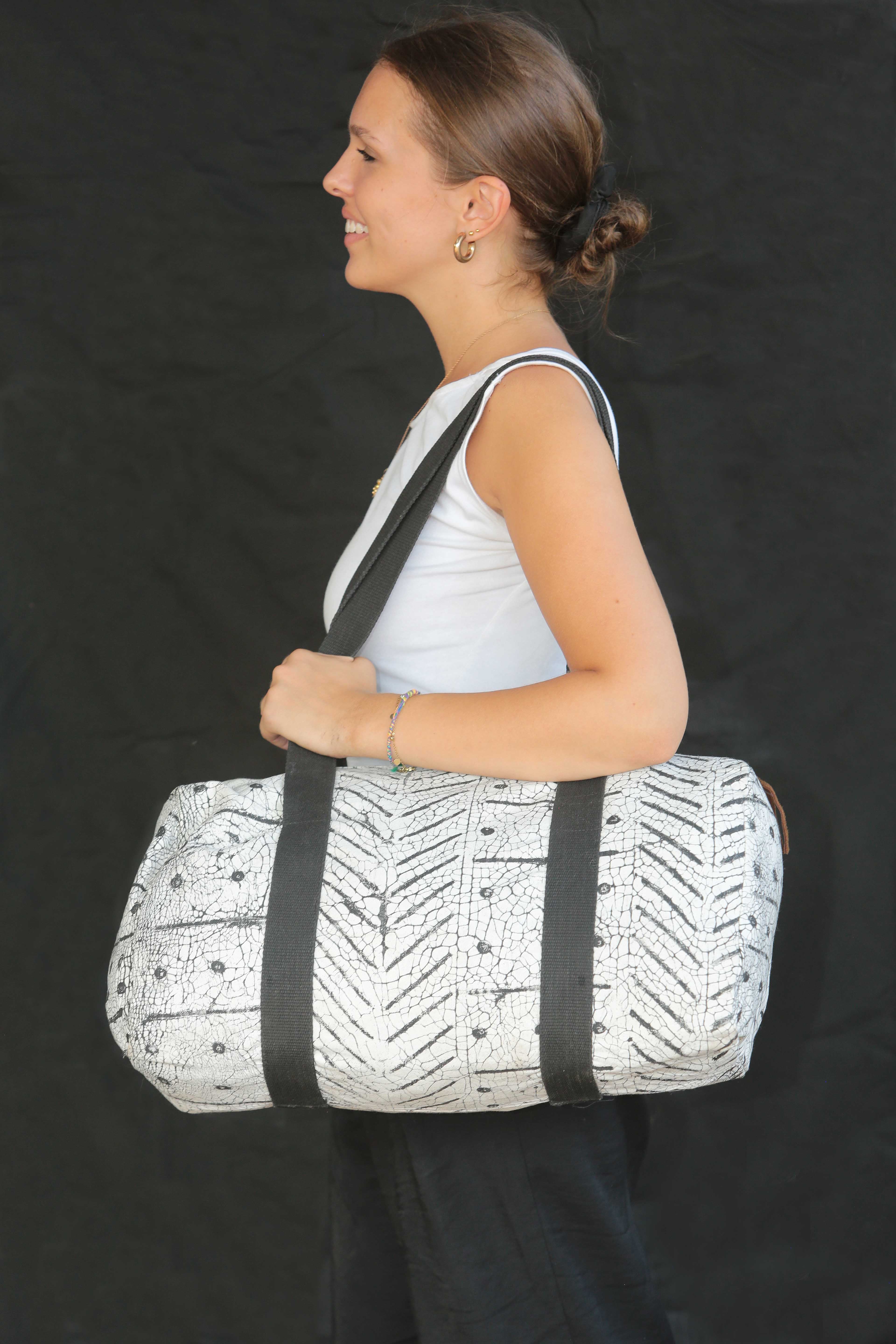 A model posing with a black and white african handcrafted printed fabric weekend bag 